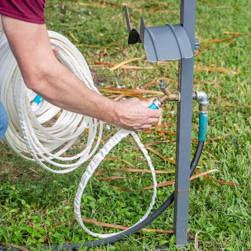 Aqua Joe 50-foot Fiberjacket RV hose being connected to a hose stand and faucet.