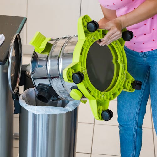 Person emptying the Sun Joe 24-volt Cordless Portable Stainless Steel Wet/Dry Vacuum Kit into the trash.