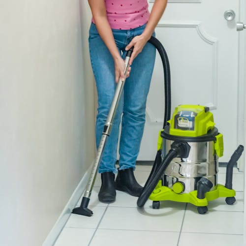 Person using the utility nozzle and telescopic tube to clean tiled floors.