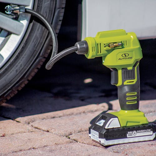Sun Joe 24-Volt Portable Cordless Air Compressor with a 1.3-Ah lithium-ion battery attached filling a car tire.