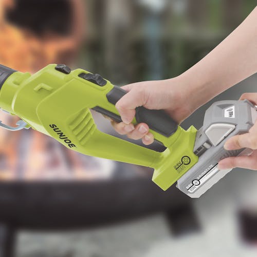 Person putting a lithium-ion battery onto the back of the Sun Joe 24-Volt cordless electric fire starter and barbeque lighter.