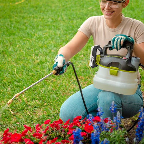 Woman using the Sun Joe 24-volt cordless Multi-Purpose Chemical Sprayer Kit to spray her flowers.