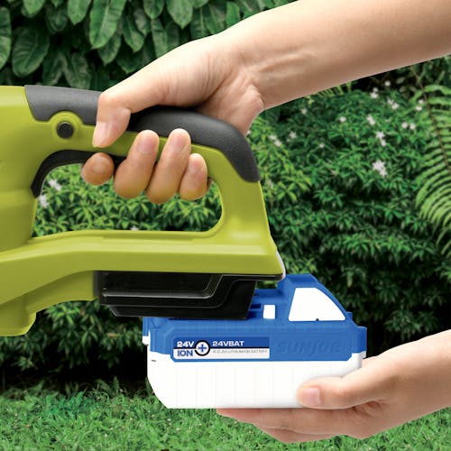 Person putting a 4.0-Ah lithium-ion battery onto the Sun Joe 24-Volt 22-inch cordless hedge trimmer.