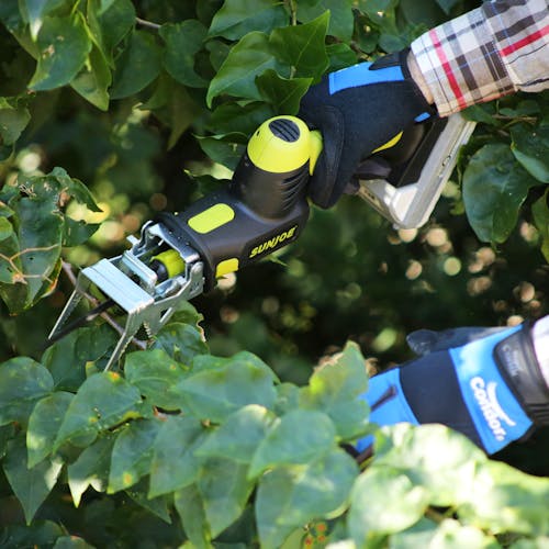 Person using the Sun Joe 24-volt Cordless All-Purpose Reciprocating Saw Kit to cut branches off a tree.