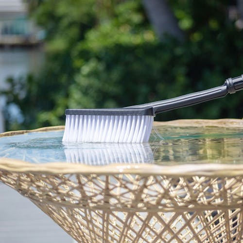 Utility brush for the Sun Joe 3-piece Power Sprayer Accessory Kit being used to clean a patio table.