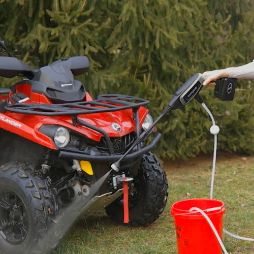 Sun Joe 24-Volt Cordless Power Cleaner in a gray color cleaning the wheels of an ATV.