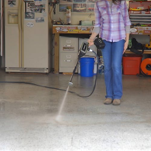 Sun Joe 24-Volt Cordless Power Cleaner in a gray color cleaning the floor of a garage.