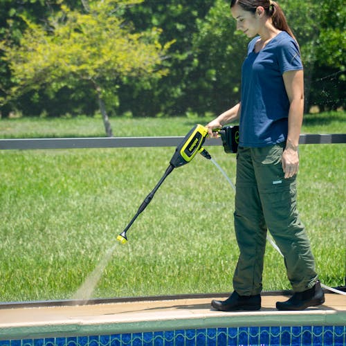 Woman using her Sun Joe 24-Volt Cordless Power Cleaner to clean around her pool area.