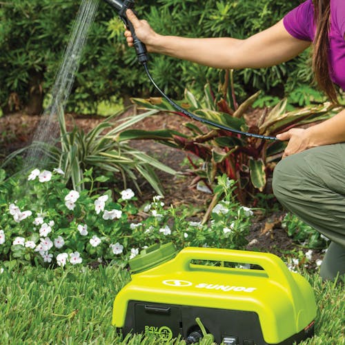 Person watering flowers with a Sun Joe 24-volt cordless portable shower spray washer.