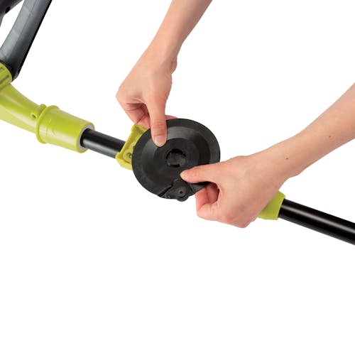 Person attaching the extra blade holder onto the shaft of the Sun Joe 24-Volt Cordless 10-inch Stringless Grass Trimmer.