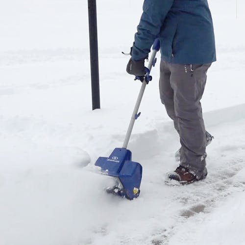 Person using the Snow Joe 24-Volt cordless 11-inch snow shovel kit to clear a path.