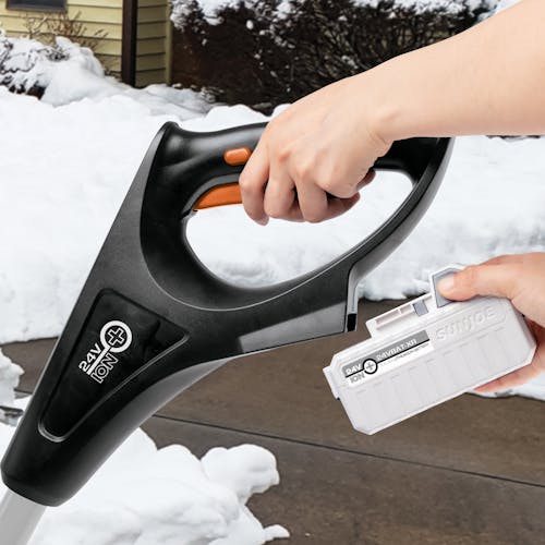 Person putting a 5.0-Ah lithium-ion battery onto the Snow Joe 24-volt cordless 12-inch snow shovel kit in orange.