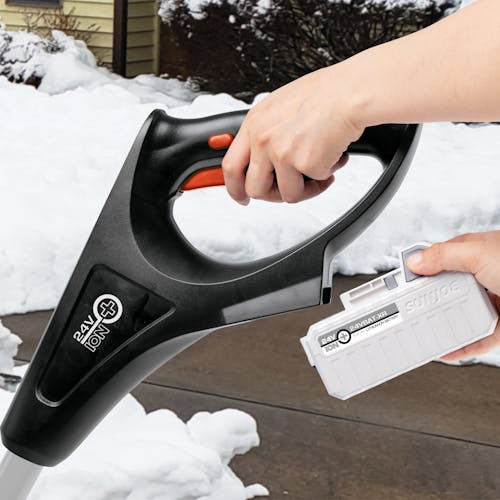 Person attaching a 5.0-Ah lithium-ion battery onto the Snow Joe 24-volt cordless 12-inch snow shovel kit in red.