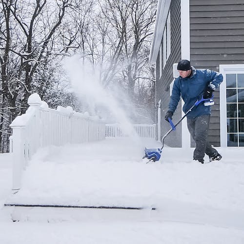 Person using the Snow Joe 24-volt cordless 13-inch snow shovel kit to clear snow off a patio.