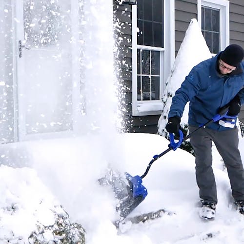 Man using the Snow Joe 24-volt cordless 13-inch snow shovel kit to clear snow off front steps.