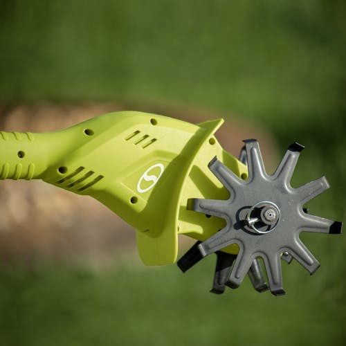 Close-up of the head and blades on the Sun Joe 24-volt cordless garden tiller and cultivating kit outside on a sunny day.