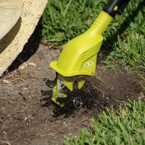 Sun Joe 24-volt cordless garden tiller and cultivating kit being used to till a patch of dirt.