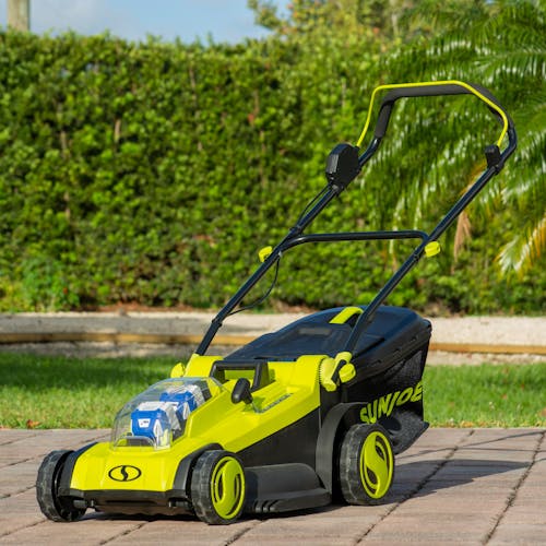 Angled view of the Sun Joe 48-volt cordless 17-inch lawn mower kit outside in a driveway.