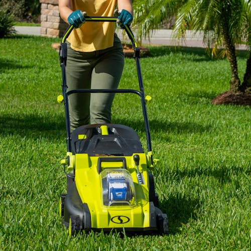 Person using the Sun Joe 48-volt cordless 17-inch lawn mower kit to mow their lawn.