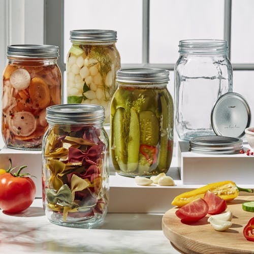 Five EatNeat 32-ounce quart wide mouth glass canning jars with airtight metal lids filled with various food on a kitchen counter.