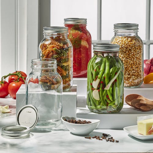 Five EatNeat 32-ounce Quart Glass Canning Jars with airtight metal lids filled with various foods on a kitchen counter.