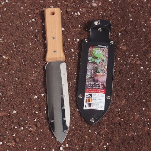 Niasku Ryohbagata 7.25-inch Japanese Stainless Steel Weeding Knife and blade sheath laying in soil.
