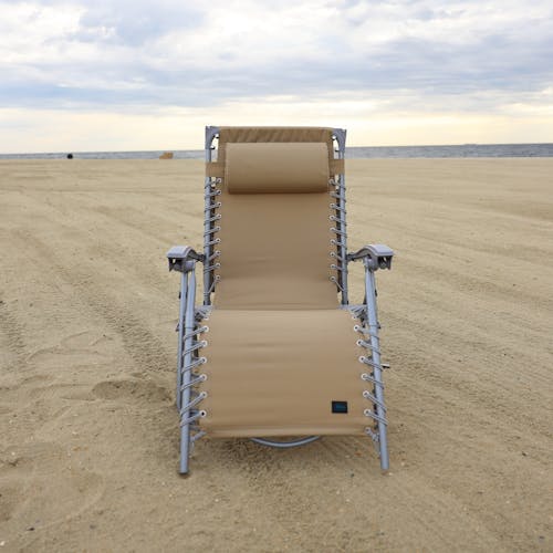 Front view of the taupe beach recliner on the sand.