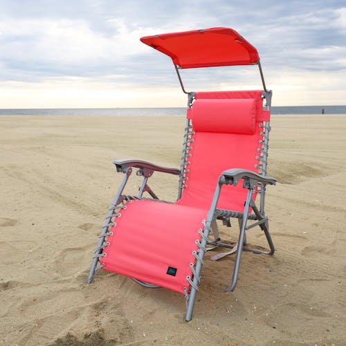 Coral beach recliner with canopy on the sand.