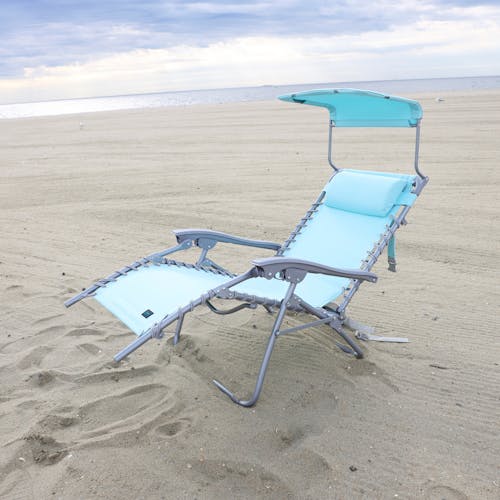 Sea glass beach recliner with canopy reclined on the sand.