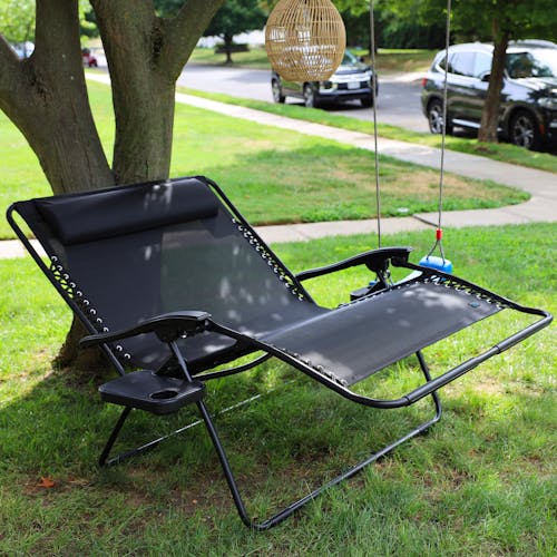 Angled view of a reclined 45-inch 2-Person Black Gravity Free Recliner under a tree.