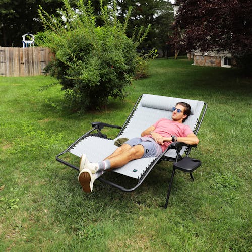 Man reclined in the 45-inch 2-Person Geometric Grey Gravity Free Recliner on a lawn.