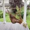 Woman sitting in the Bliss Hammocks 40-inch Brown Island Rope Hammock Chair hanging on a front porch.