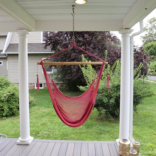 Bliss Hammocks 40-inch Pink Island Rope Hammock Chair hanging on a front porch.