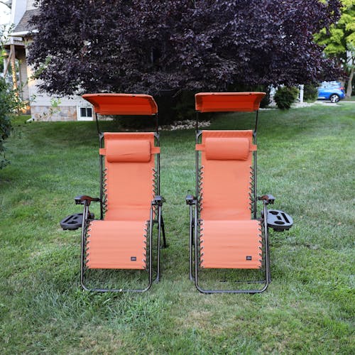 Set of 2 26-inch terracotta gravity free chairs placed on a lawn.