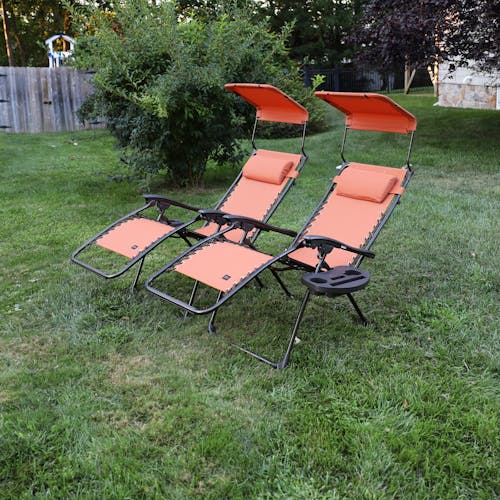 Angled view of a set of 2 26-inch terracotta gravity free chairs reclined on a lawn.