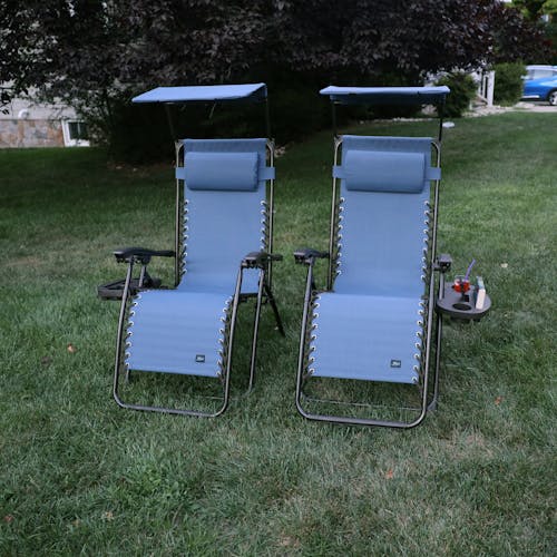 Set of 2 26-inch denimb blue gravity free chairs placed on a lawn.