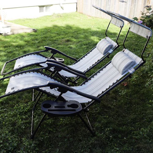 Set of 2 26-inch casual stripe gravity free chairs reclined on a lawn.