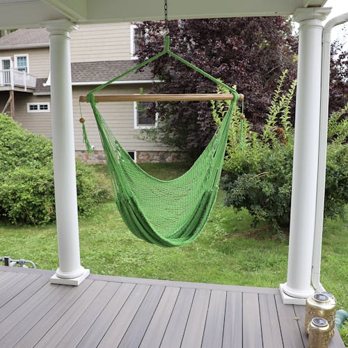 Bliss Hammocks 40-inch Light Green Island Rope Hammock Chair hanging on a front porch.