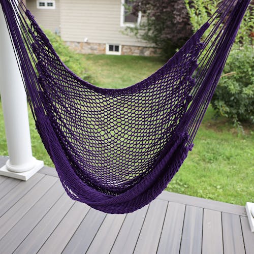 Close-up of the Bliss Hammocks 40-inch Purple Island Rope Hammock Chair hung on a front porch.