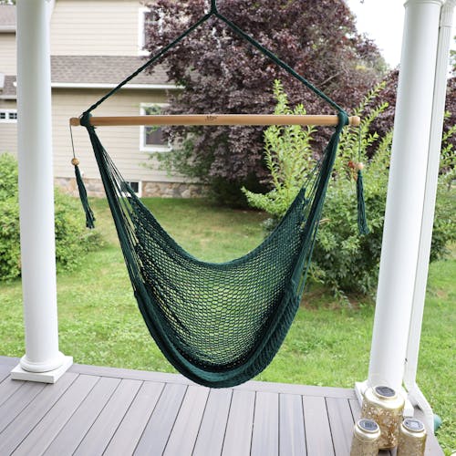 Bliss Hammocks 40-inch Green Island Rope Hammock Chair hanging on a front porch.