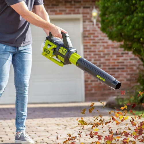Person using the Sun Joe 48-volt cordless brushless turbine leaf blower to blow leaves off a driveway.