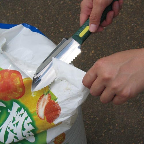 Nisaku Hori Hori 5-inch Mini Stainless Steel Knife being used to open a plastic bag.