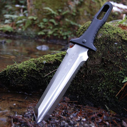 Niasku Miyamatou 7.5-inch Japanese Stainless Steel Knife stuck in the dirt next to a stream.