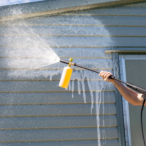 Sun Joe 34-ounce Foam Cannon for SPX Series Electric Pressure Washers being used to clean the side of a house.