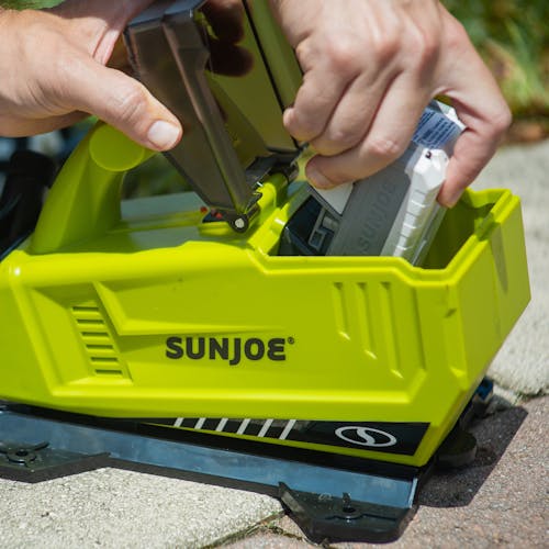 Person inserting a 2.0-Ah lithium-ion battery into the Sun Joe 24-volt Cordless 5.0-GPM Transfer Pump.