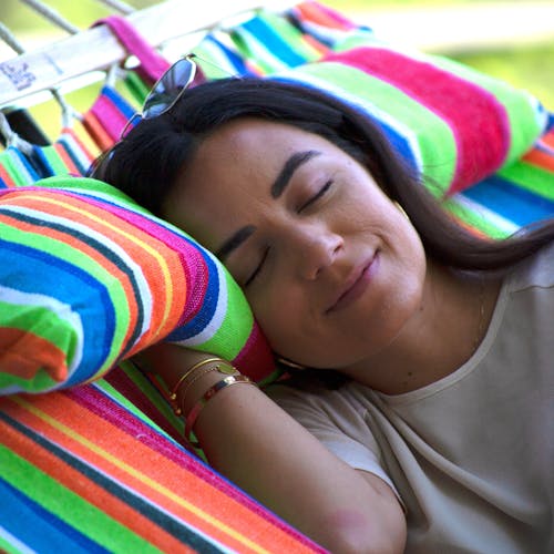 Woman taking a nap on the Bliss Hammocks 48-inch Wide Tropical Fruit Caribbean Hammock.