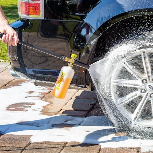 Sun Joe 34-ounce Foam Cannon for SPX Series Electric Pressure Washers being used to clean a car tire.