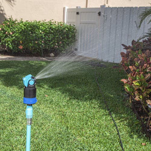 Aqua Joe Indestructible Turbo Drive 360 Degree Telescoping Tripod Lawn and Garden Sprinkler and Mister watering a lawn.