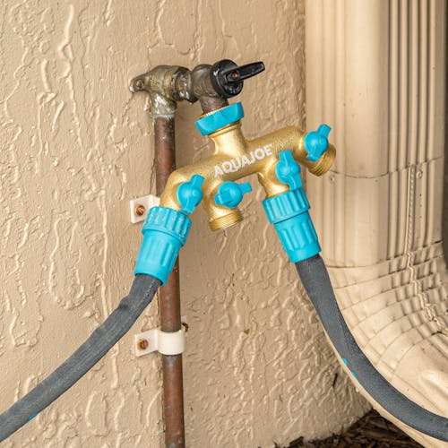 Aqua Joe 4-way brass Garden Hose Splitter connected to a faucet and 2 hoses.