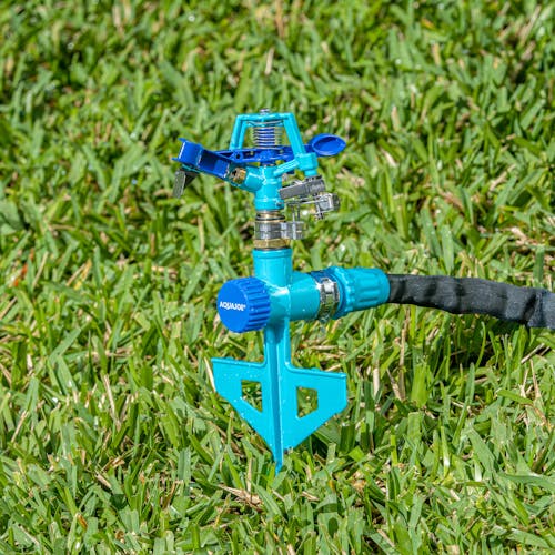 Aqua Joe Indestructible Zinc Impulse 360 Degree Sprinkler staked in the ground connected to a hose.
